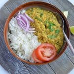 white urad dal and rice served in a grey bowl with cut onions and sliced tomato.