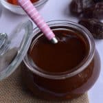 imli chutney or tamarind chutney is stored in the glass jar. dates are scattered around it.