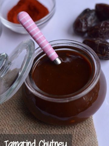 imli chutney or tamarind chutney is stored in the glass jar. dates are scattered around it.