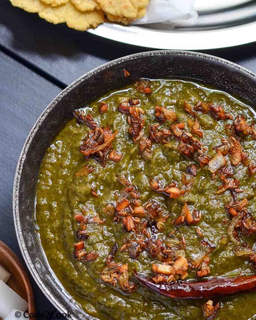 a close sarson ka saag click served in black bowl & garnished with tempering