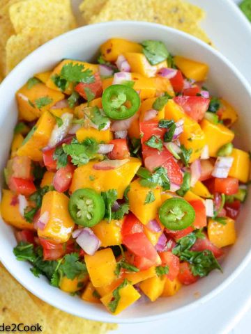 a close up click of mango salsa served in white bowl