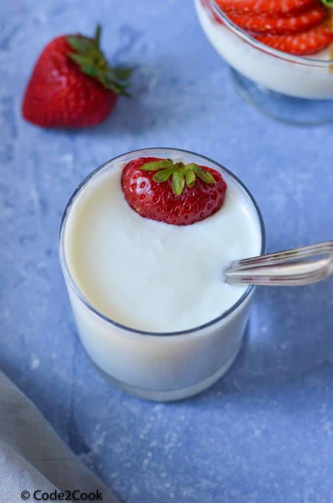 homemade yogurt is served in glass with strawberry.