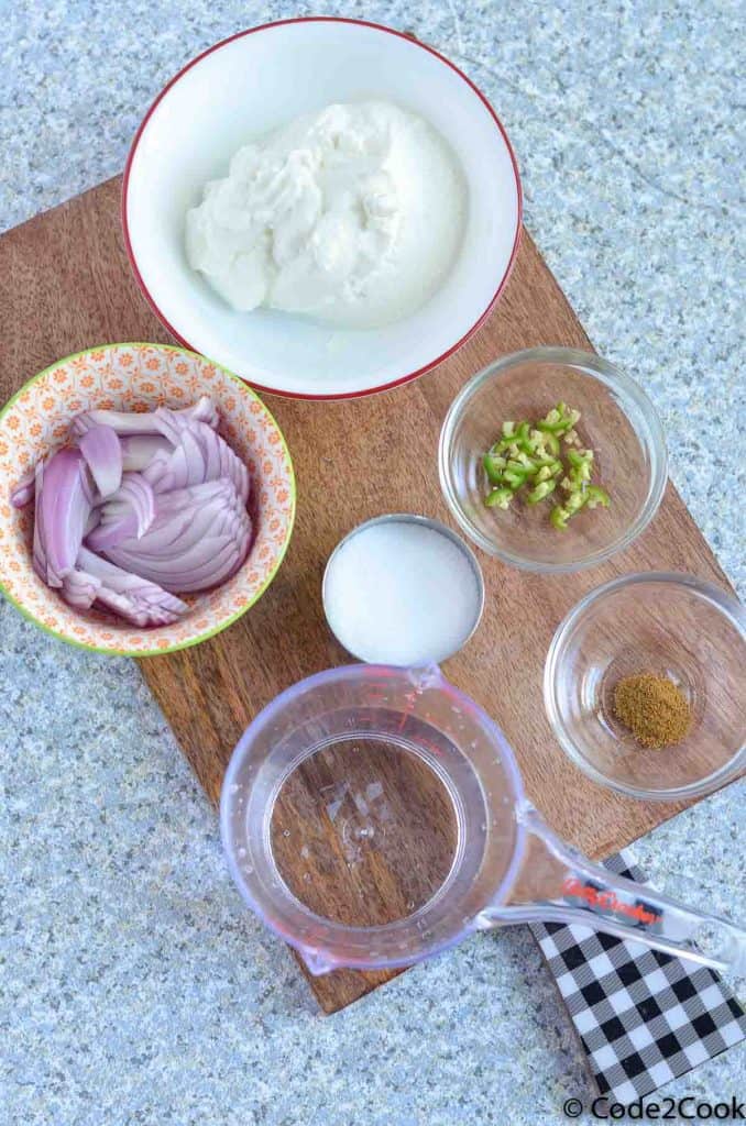 onion raita ingredients kept in glass bowls ver wooden board