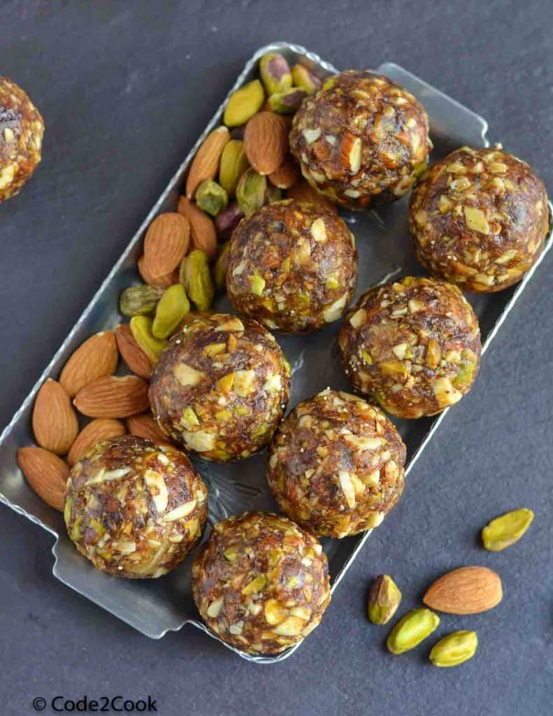 over head shot of dry fruits laddu with dates kept in a silver plate.