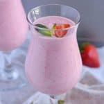 Close up click of strawberry lassi served in glasses and garnished with mint leaves