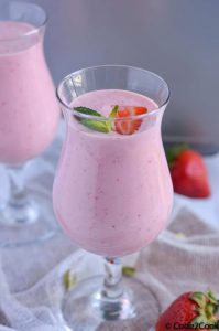 Close up click of strawberry lassi served in glasses and garnished with mint leaves