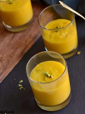 Aamras served in three small glasses and garnished with chopped nuts