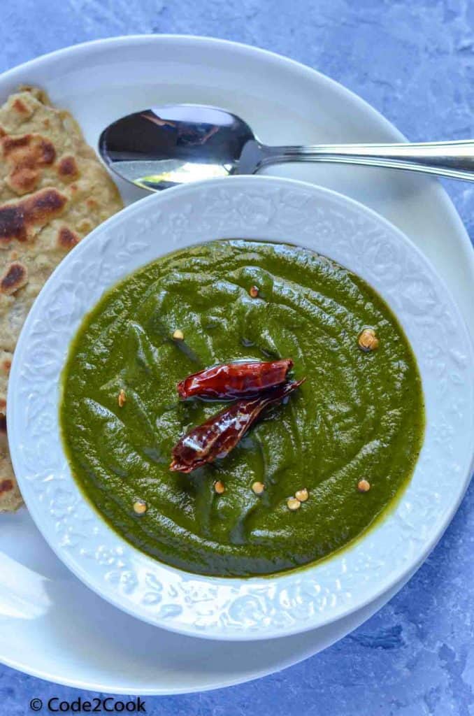 spinach chutney served in white bowl with red chili garnishing