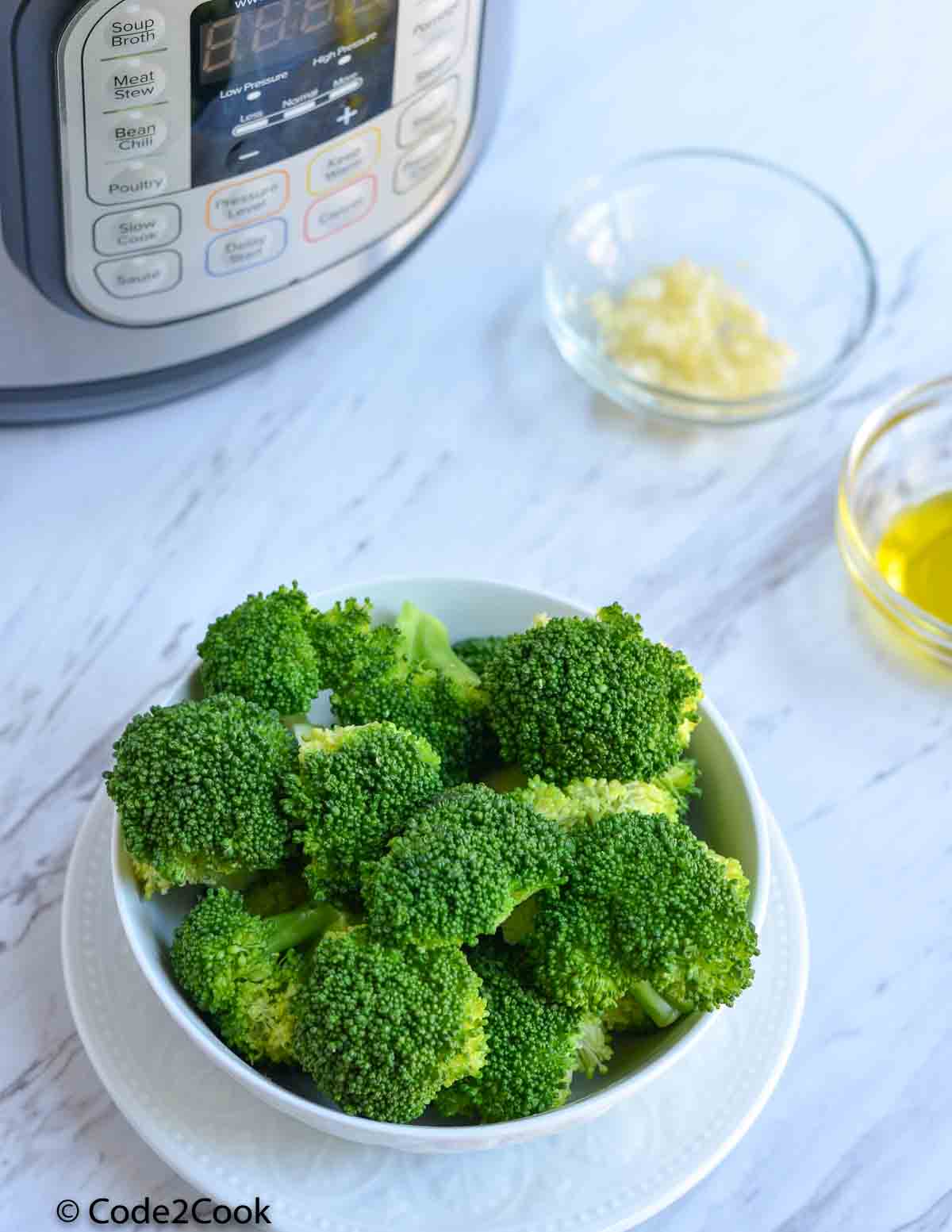 steamed broccoli served in white bowl and placed near instant pot.