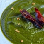 A close up click of palak chutney with dry red chili tempering